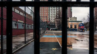 View of concrete schoolyard in New York City through fence